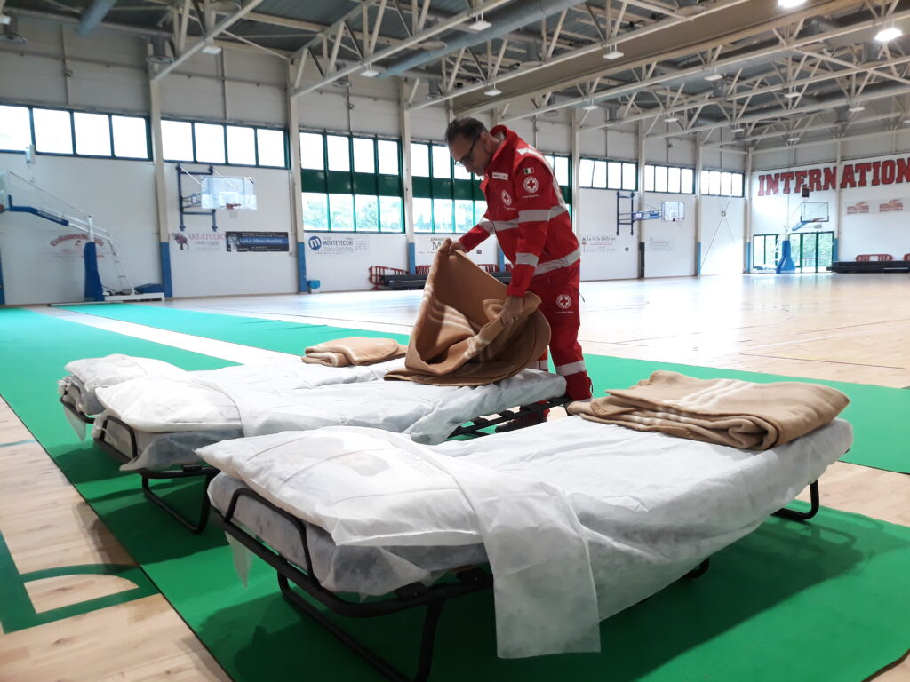 Volontari del Comitato di Imola della Croce Rossa Italiana impegnati nel preparare la Palestra Ravaglia per gli sfollati