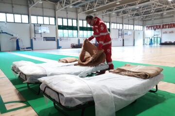 Volontari del Comitato di Imola della Croce Rossa Italiana impegnati nel preparare la Palestra Ravaglia per gli sfollati